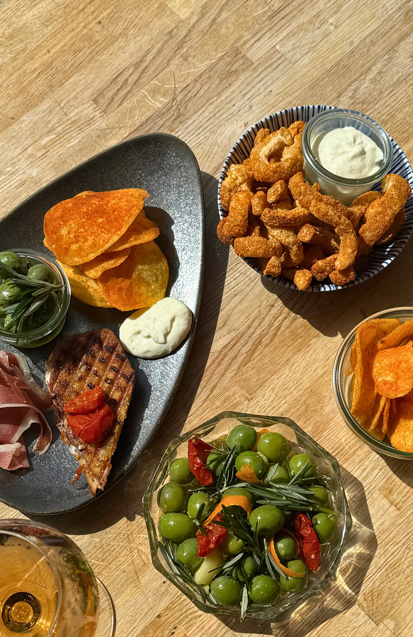 Små bidder, oliven, lufttørret skinke og sprøde snacks serveret med vin hos Pica Pica i Aarhus.